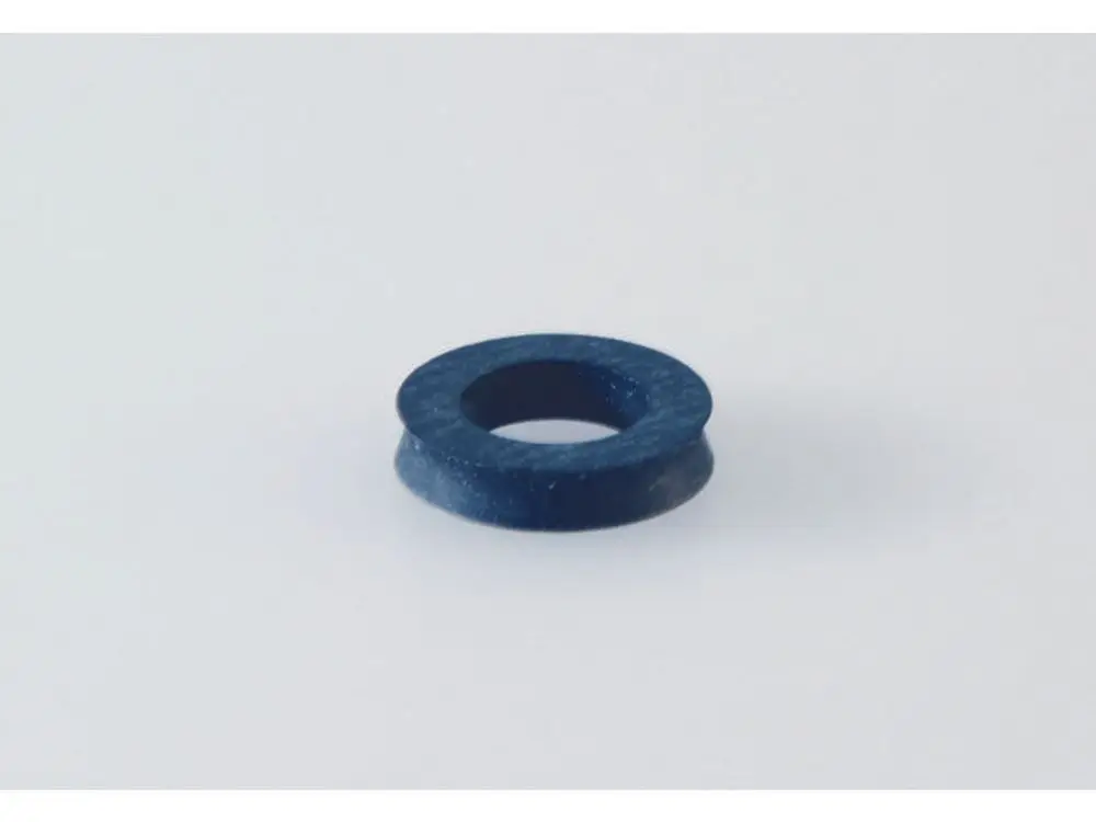 Runde, flache Dichtung in dunkler Farbe, möglicherweise aus Gummi oder Kunststoff, liegt auf einer neutralen Oberfläche. Produkt von Ideal Standard.